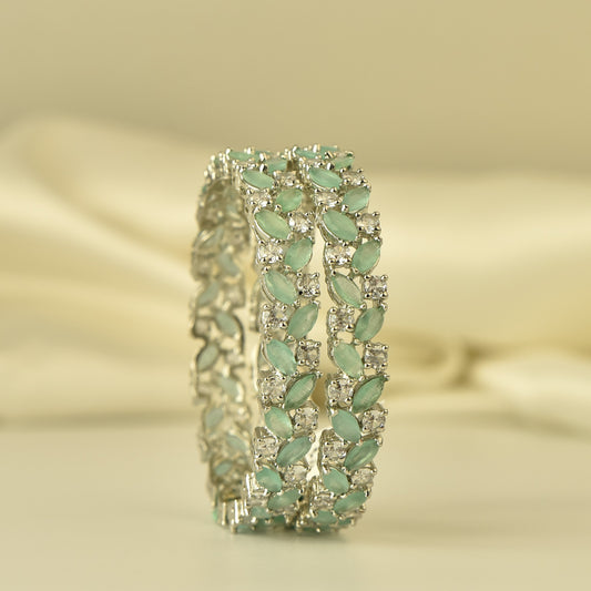 silver polish ad bangle with leaf-like stones on a beige background