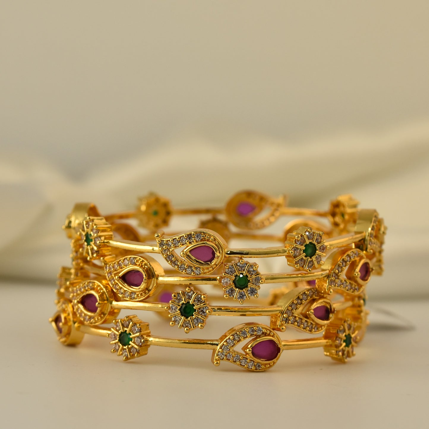 AD Bangle with Gold Polish looks like real Diamond bangle with green and ruby color stone arranged in beautiful mango motif stylish design